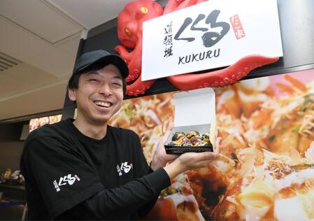 　限定メニューを手に笑顔を見せる「たこ家道頓堀くくる」責任者の田中辰也さん（撮影・石井剣太郎）