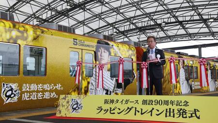 　ラッピングトレインを背にあいさつをする粟井社長（撮影・中田匡峻）