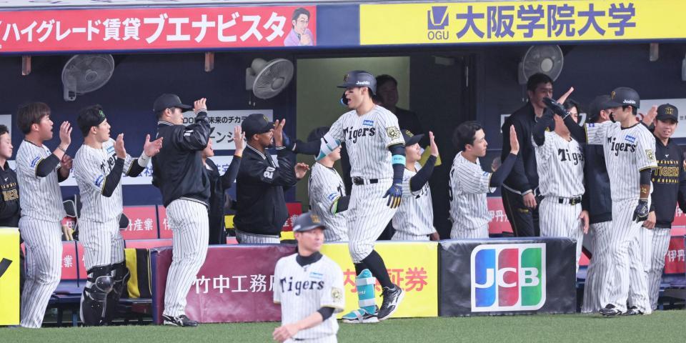 　８回、同点２ランを放ちベンチの出迎えにタッチを交わして応じる佐藤輝（中央）＝撮影・立川洋一郎