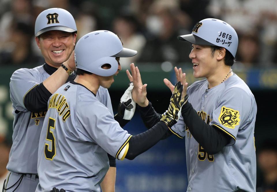 ３回、勝ち越し２ランを放った近本（５）を迎える富田。奥は筒井外野守備兼走塁チーフコーチ（撮影・中田匡峻）