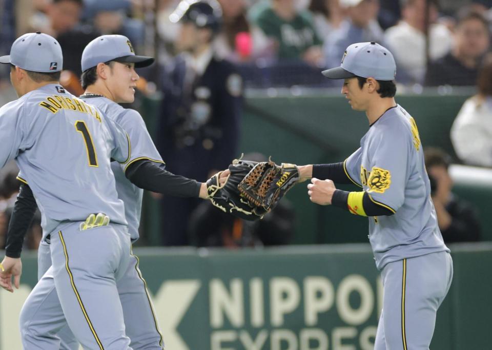 ２回、好返球でピンチを救った近本（右）とタッチする富田（撮影・西岡正）