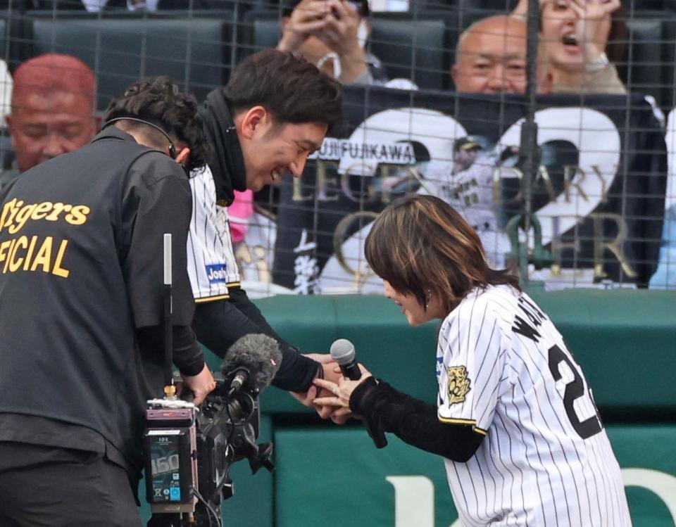 　歌唱を終えた渡瀬マキ（右）と握手を交わす藤川監督（撮影・中田匡峻）