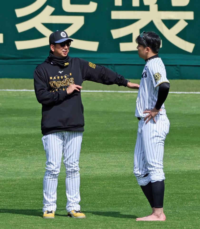 　練習の合間に藤川監督（左）に声を掛けられ話を聞く才木（撮影・立川洋一郎）