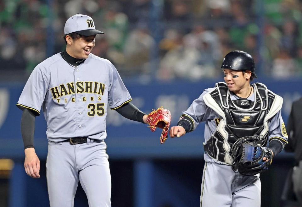 　６回、才木（左）とタッチを交わす梅野