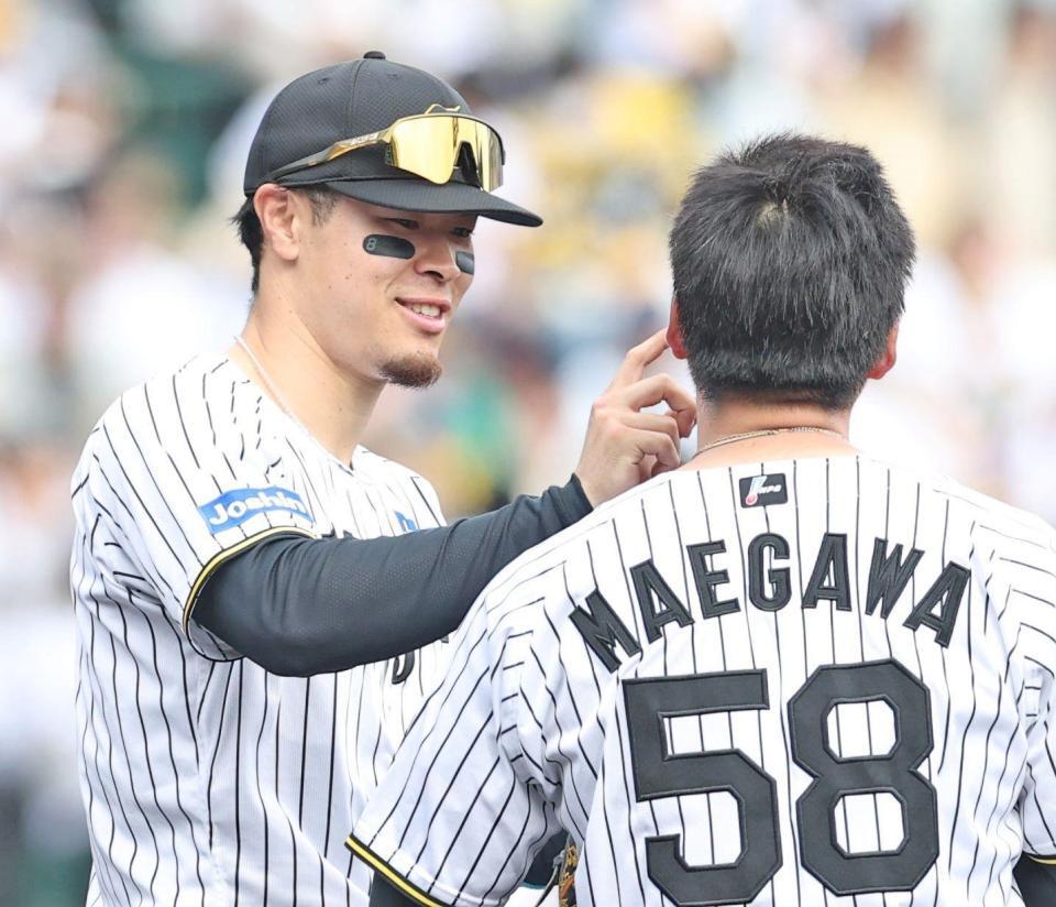 　５回の守備を前に前川の顔に付いた汚れを取る佐藤輝（撮影・中田匡峻）