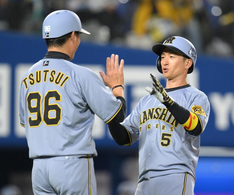 　７回、右越えソロを放ち、筒井コーチ（左）に迎えられる近本（撮影・伊藤笙子）