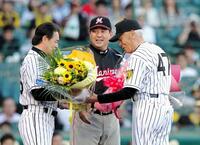 　セレモニーで阪神・和田監督（左）から花束を受け取り笑顔をみせる小山正明氏。中央はロッテ・伊東監督=２０１５年