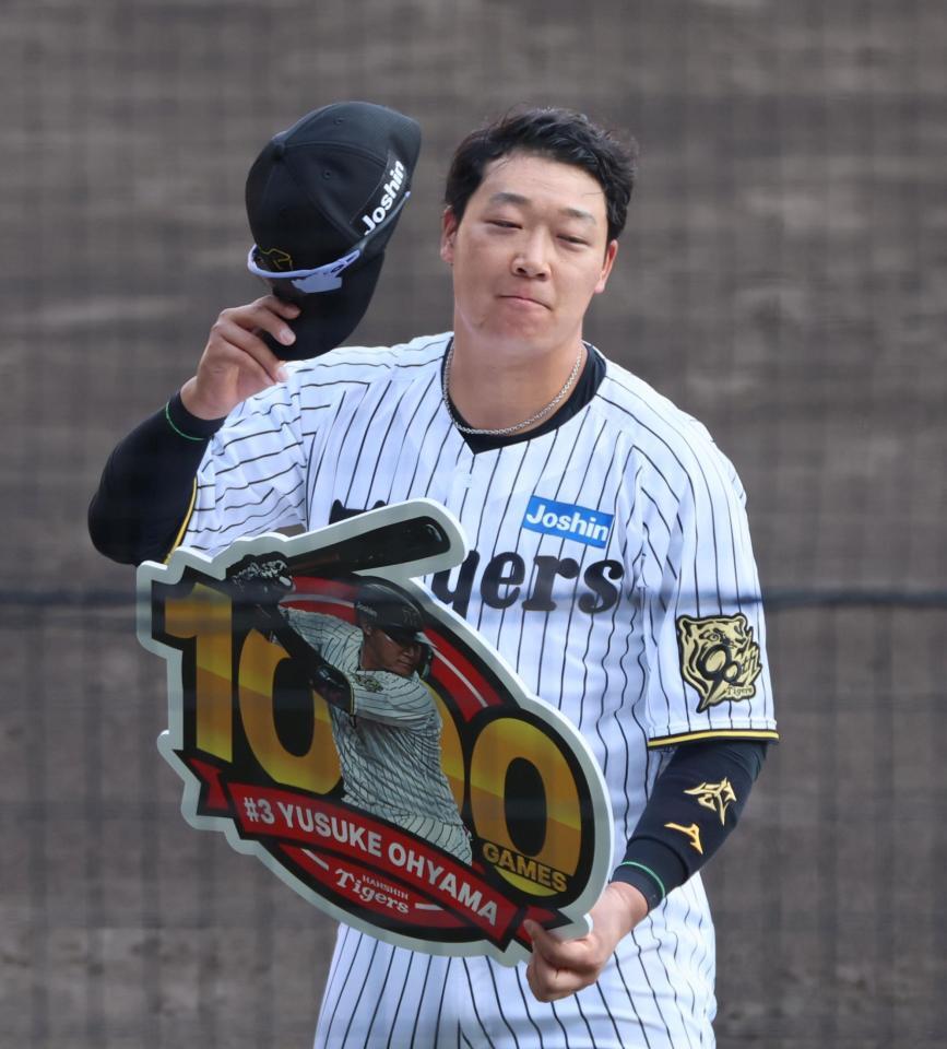 　１０００試合出場の記念ボードを手にする大山（撮影・立川洋一郎）