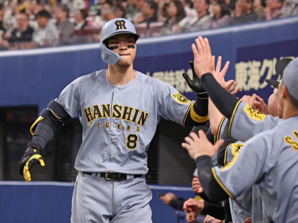　４回、ライトへ同点ソロを放ち、ナインとタッチを交わす佐藤輝（撮影・中田匡峻）
