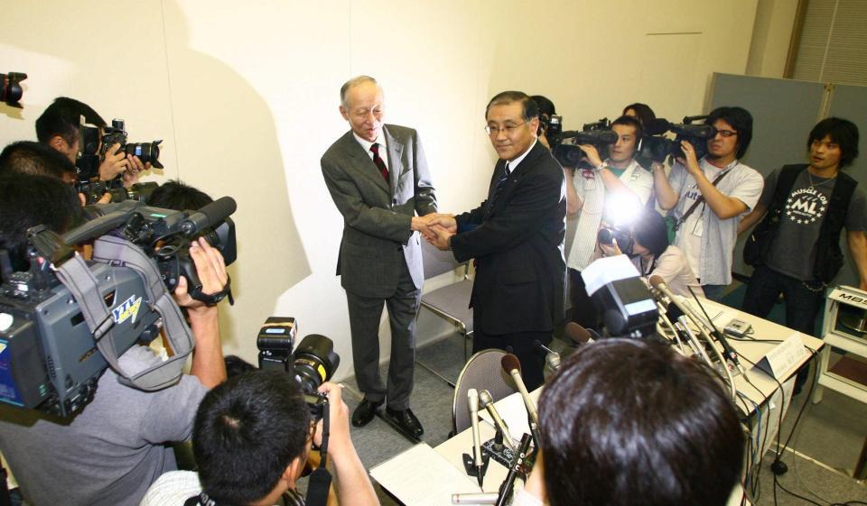 　会見後ガッチリ握手する阪急ＨＤ・角和夫社長（左）と阪神電鉄・坂井信也常務取締役＝２００６年６月