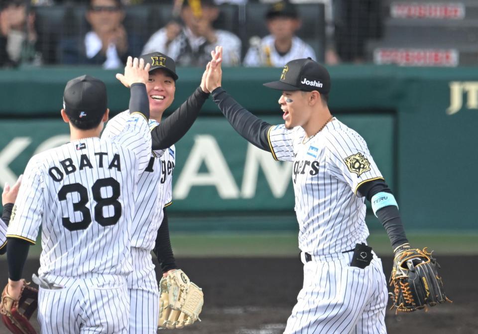 　村上と勝利のハイタッチを交わす佐藤輝（撮影・飯室逸平）