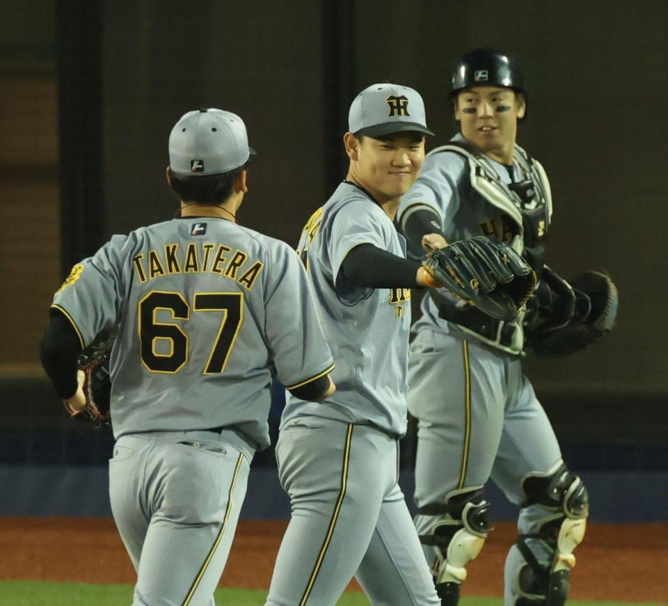 １０回、ピンチを脱し阪神・高寺（６７）と笑顔でタッチする及川（中央）＝撮影・金田祐二