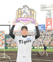 　通算１００セーブ達成の記念ボードを掲げる岩崎（撮影・西田忠信）