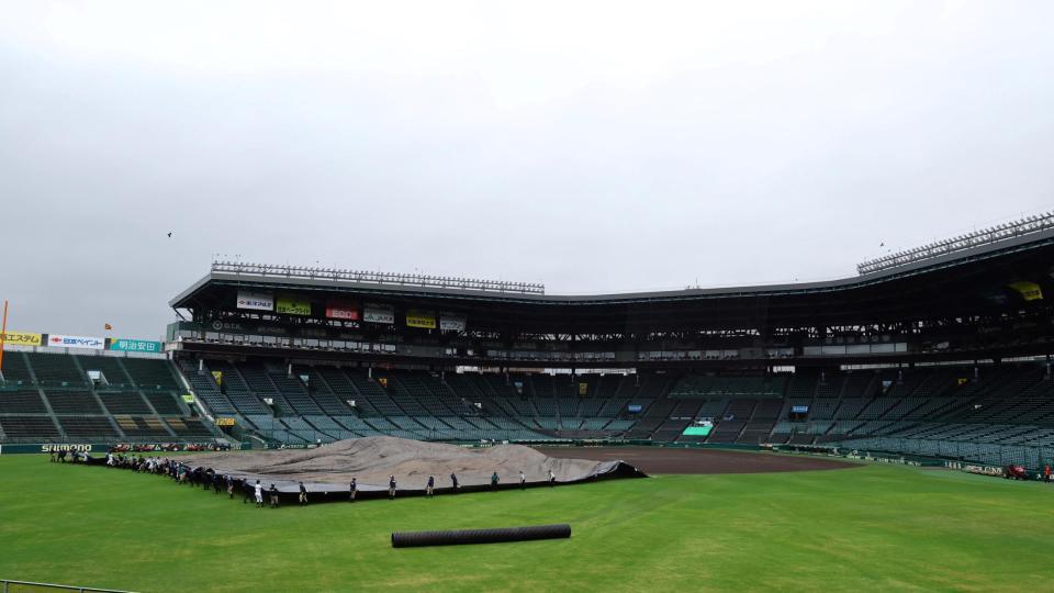 　雨が上がり、グラウンドのシートがめくられる（撮影・山口登）