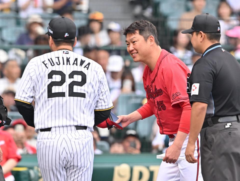 　藤川監督（２２）とメンバー表を交換し笑顔を見せる新井監督（撮影・西田忠信）