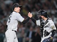 　完封勝利を挙げた才木は好リードの梅野と握手を交わす（撮影・田中太一）