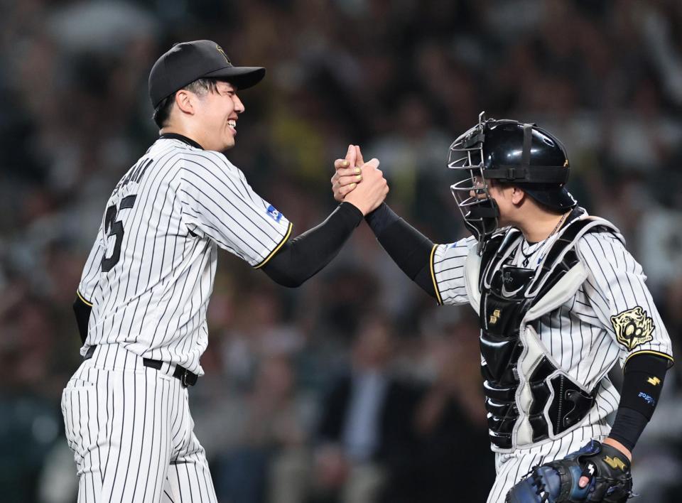 　完封勝利を挙げた才木は好リードの梅野と握手を交わす（撮影・田中太一）