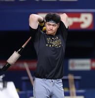 　バットで体をほぐす佐藤輝（撮影・北村雅宏）