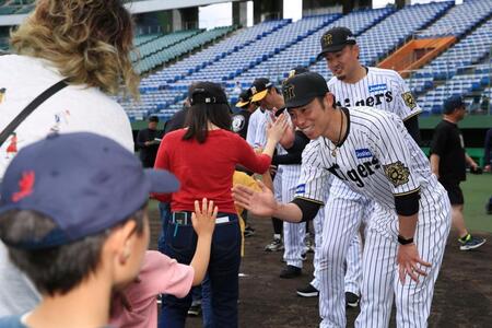 　イベント後に参加者とハイタッチする阪神ＯＢの江越氏（右）と秋山氏（右から２人目）＝球団提供