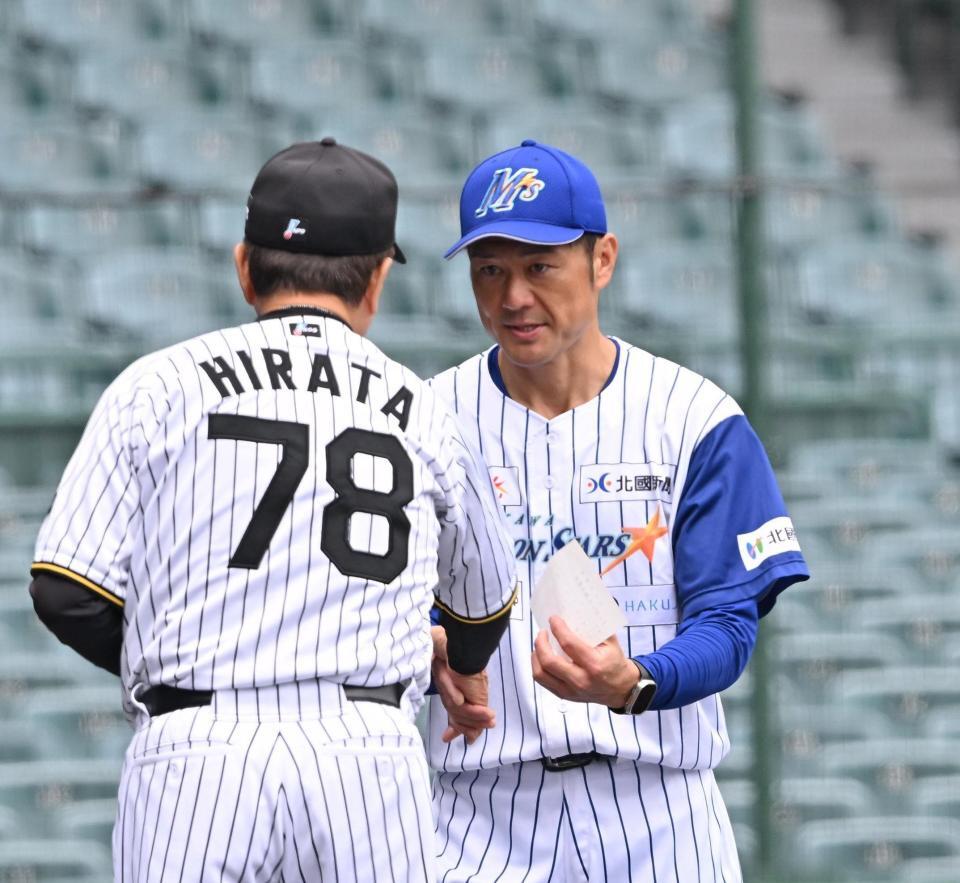 　平田２軍監督（左）とメンバー表の交換をする石川・岡崎太一監督（撮影・西田忠信）