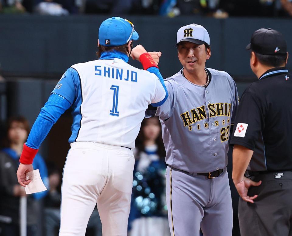 メンバー表を交換し、新庄監督（左）とグータッチを交わす藤川監督（撮影・中島達哉）