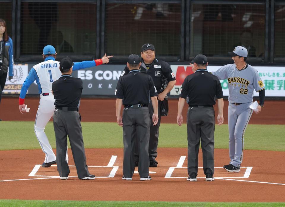 　メンバー表交換で新庄監督（左）、審判団と手を合わせた後、打ち合う藤川監督（撮影・西岡正）