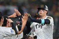 　８回、２ランを放ち、ナインとタッチを交わす佐藤輝（撮影・北村雅宏）