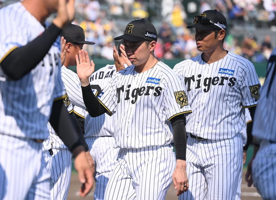 　試合に勝利し、ナインとタッチを交わす石井（中央）＝撮影・西田忠信