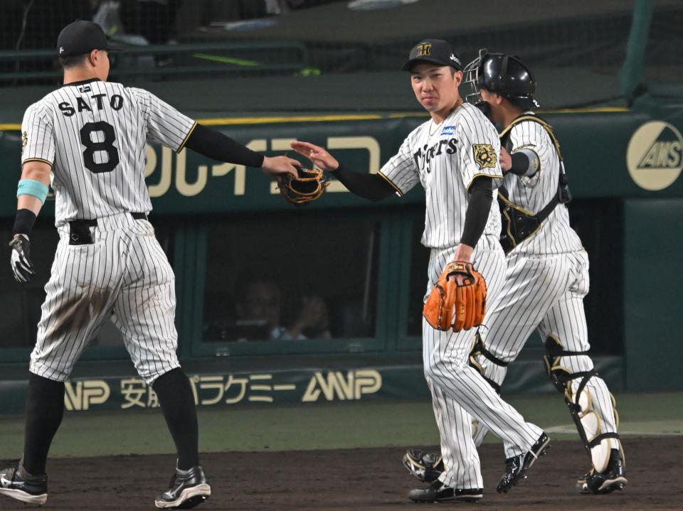 　８回、好リリーフを見せ佐藤輝（８）らとタッチを交わす石井（撮影・飯室逸平）