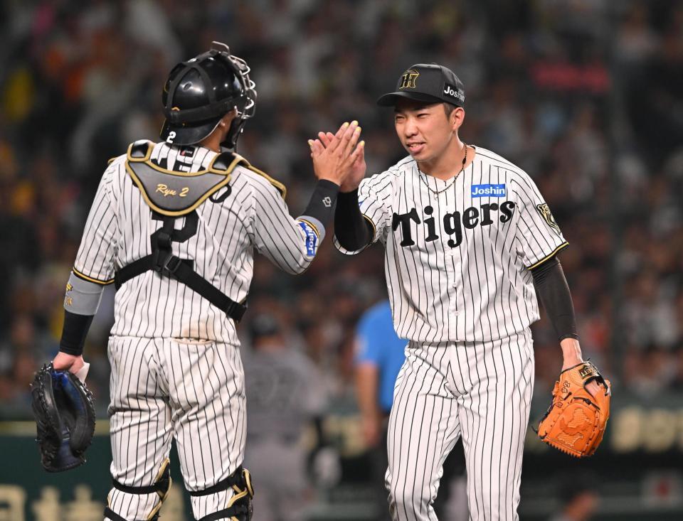 　８回を無失点に抑え、梅野（左）とタッチを交わす石井（撮影・西田忠信）