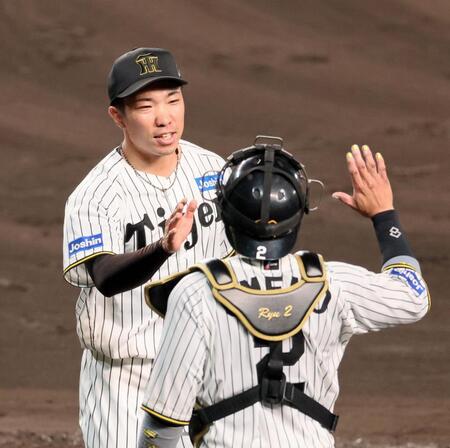 　８回に登板して１イニングを無失点に抑え、梅野（右）とタッチを交わす石井（撮影・立川洋一郎）