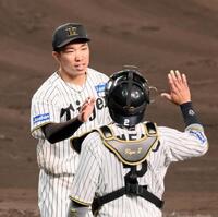 　８回に登板して１イニングを無失点に抑え、梅野（右）とタッチを交わす石井（撮影・立川洋一郎）