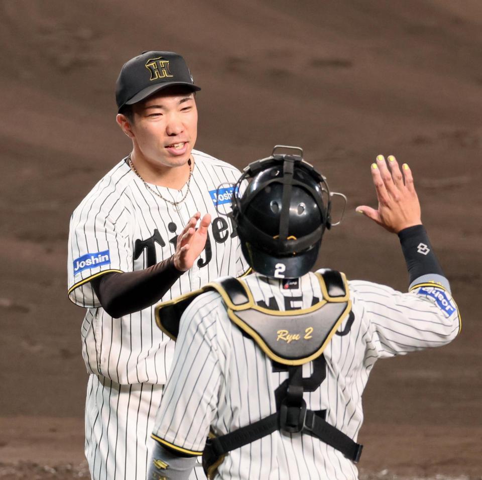 　８回に登板して１イニングを無失点に抑え、梅野（右）とタッチを交わす石井（撮影・立川洋一郎）