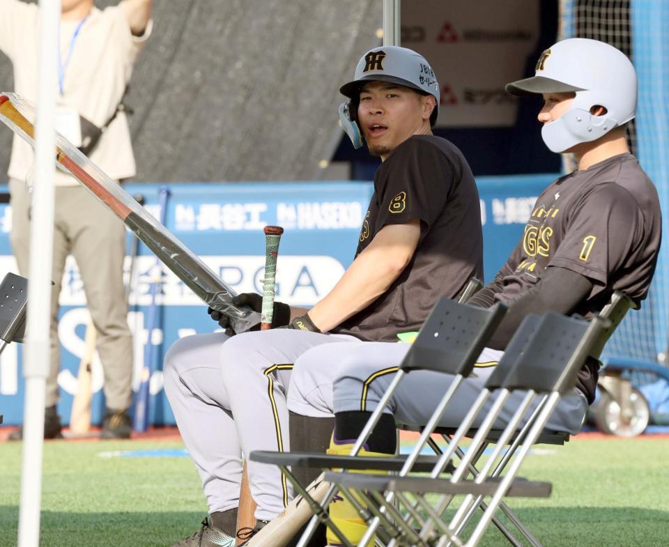 　打撃ケージ後ろに設置された日よけテントに座る佐藤輝（左）と森下（撮影・田中太）