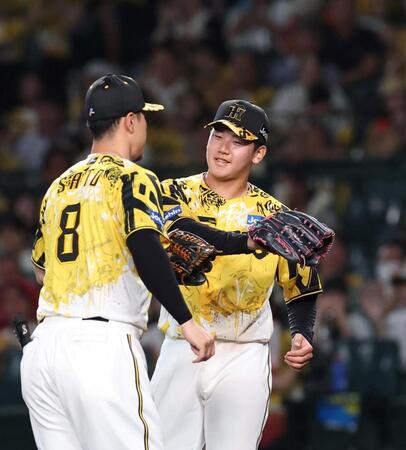 　３回、古賀を三ゴロ併殺打に仕留め、佐藤輝とグラブタッチを交わす門別（右）＝撮影・北村雅宏