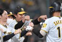 　８回、送りバントを決めた坂本を迎える藤浪（中央）ら＝２０２２年