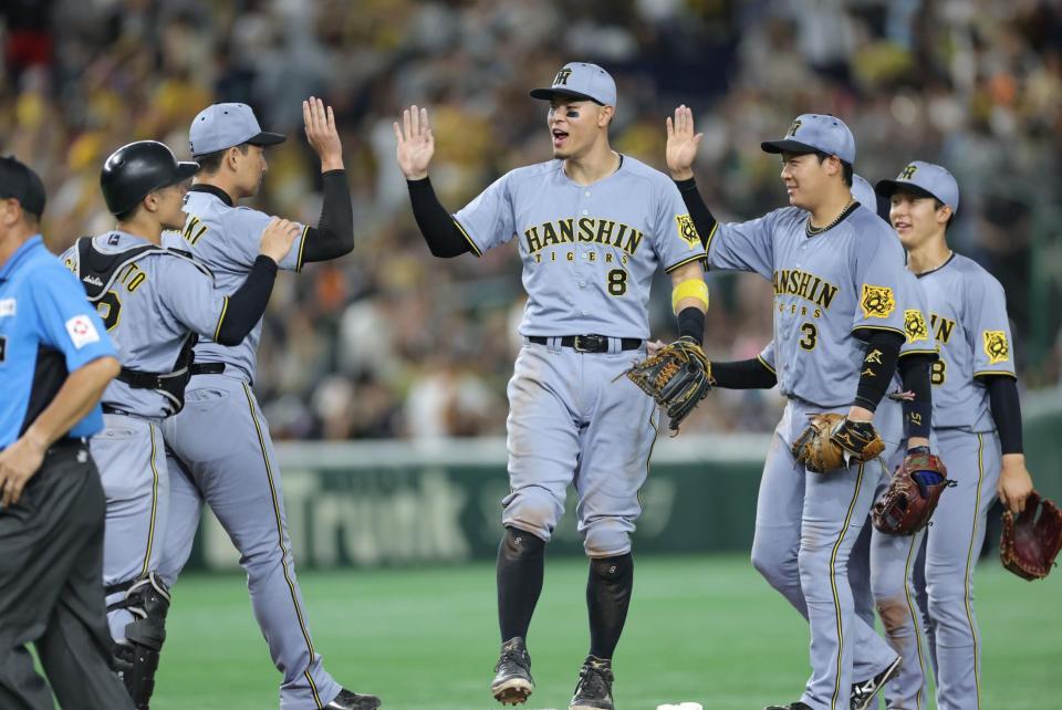 　巨人に勝利し、ナインとタッチを交わす佐藤輝（中央）＝撮影・西岡正