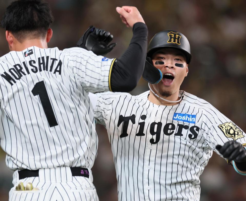 　６回、ソロを放って生還し森下（左）とタッチを交わす佐藤輝（撮影・立川洋一郎）