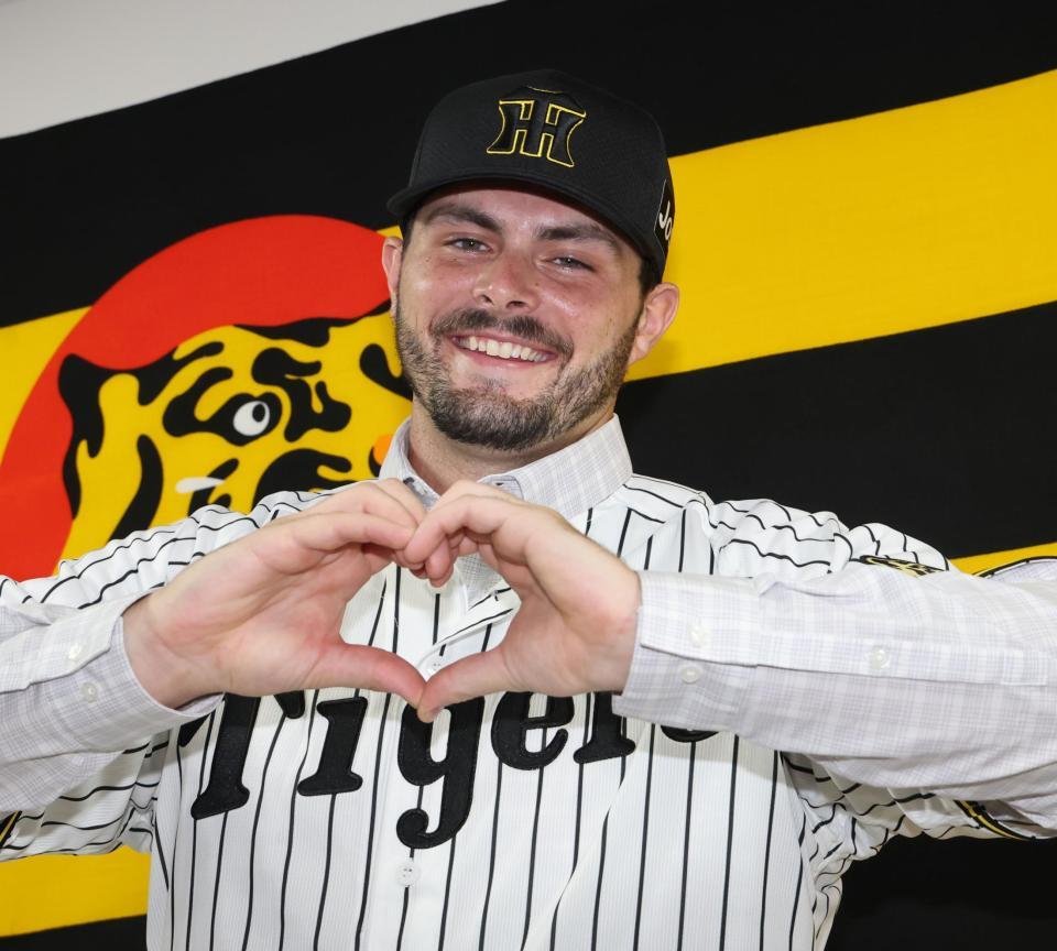 　笑顔でハートマークをつくるハートウィグ（撮影・田中太一）