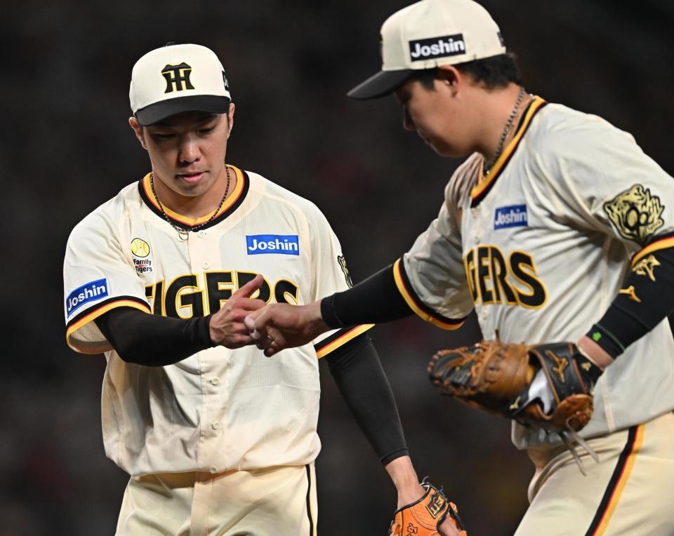 　８回を無失点に抑え、大山（右）とグータッチする石井（撮影・西田忠信）