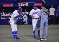 　落合２軍監督（左）から贈呈品を手渡される平田２軍監督（手前）