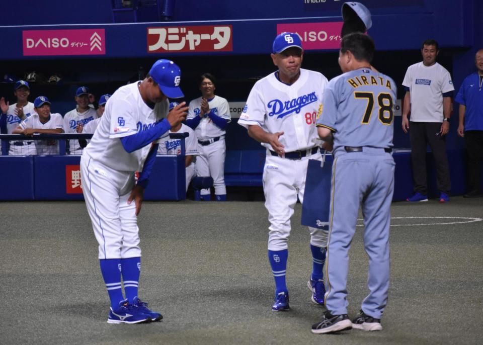 　落合２軍監督（左）から贈呈品を手渡される平田２軍監督（手前）