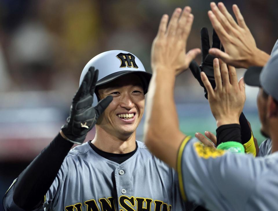 　１０回、佐藤輝の適時打で生還した近本はナインとタッチを交わす（撮影・田中太一）