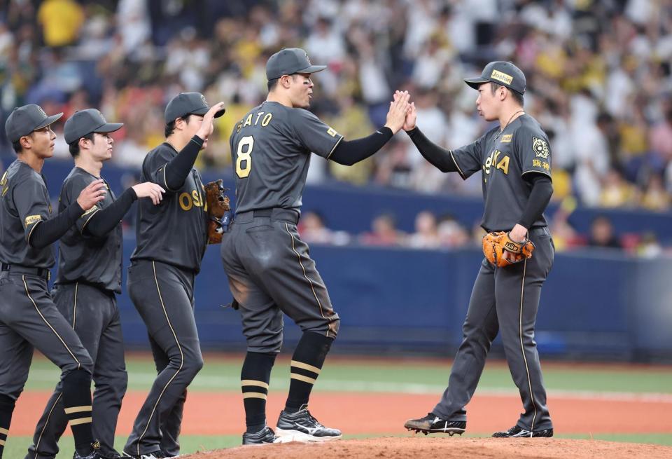 　最後を締めた石井（右）は佐藤輝らとタッチを交わす（撮影・北村雅宏）