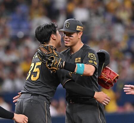 　完投勝利した才木（左）と抱き合う佐藤輝（撮影・西田忠信）