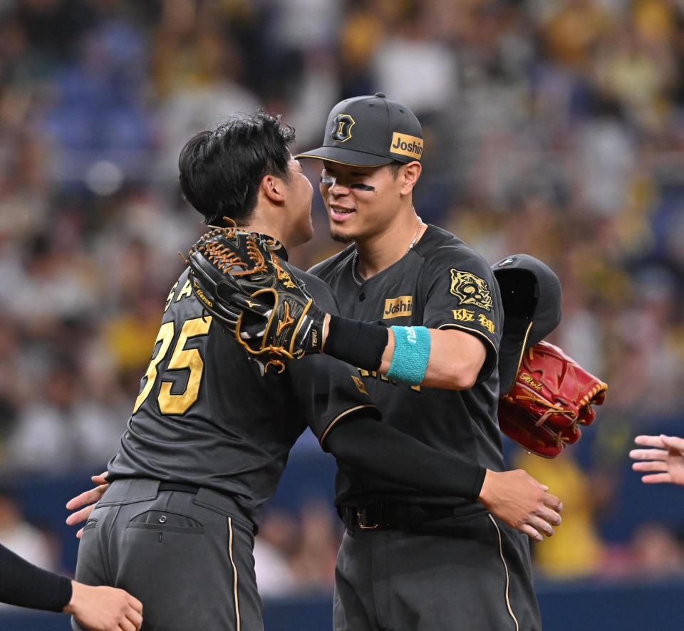 　完投勝利した才木（左）と抱き合う佐藤輝（撮影・西田忠信）