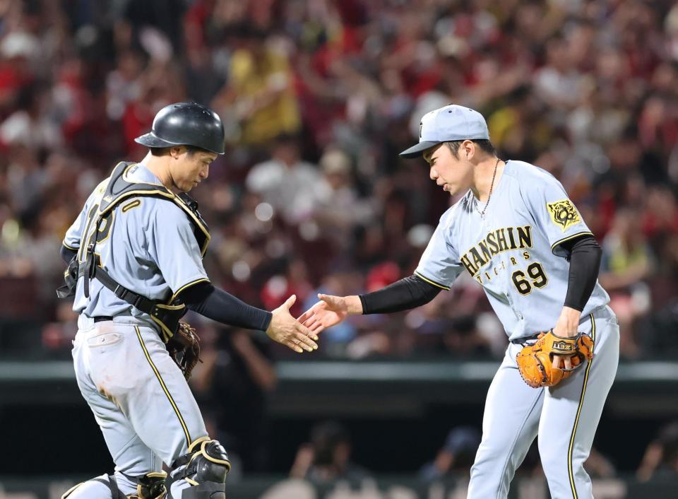 　９回を無失点で締め、坂本と握手をする石井（撮影・市尻達拡）