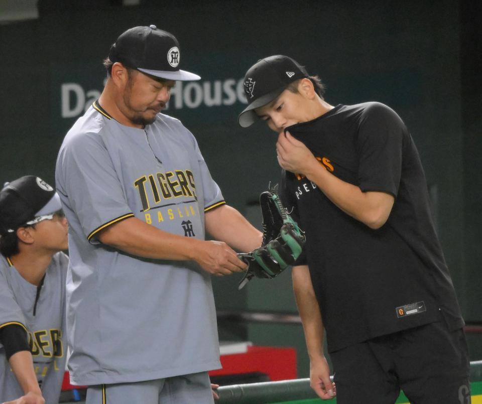 　門脇（右）のグラブを見つめる小谷野コーチ（撮影・伊藤笙子）