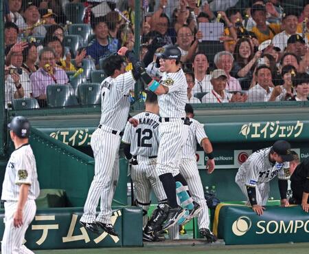 　８回、２者連続となるソロアーチを放ち、ベンチ前で森下（中央左）とタッチを交わす佐藤輝（撮影・立川洋一郎）