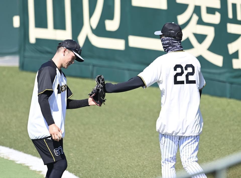 　守備練習中の高寺とタッチを交わす藤川監督